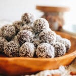 Close up shot of almond joy energy balls stacked on a wooden platter.