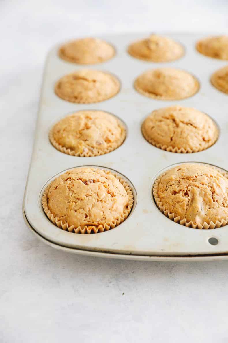 baked carrot cake muffins in a metal muffin tin.