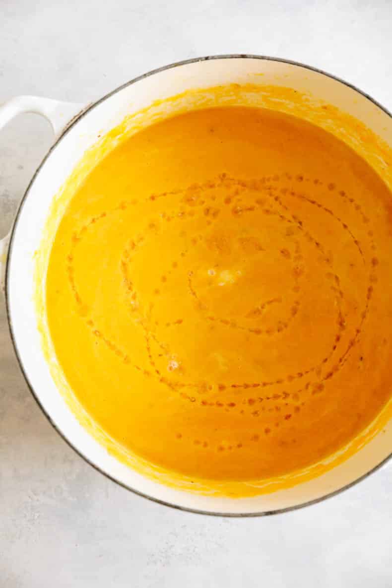 blended ginger carrot soup in a white dutch oven.