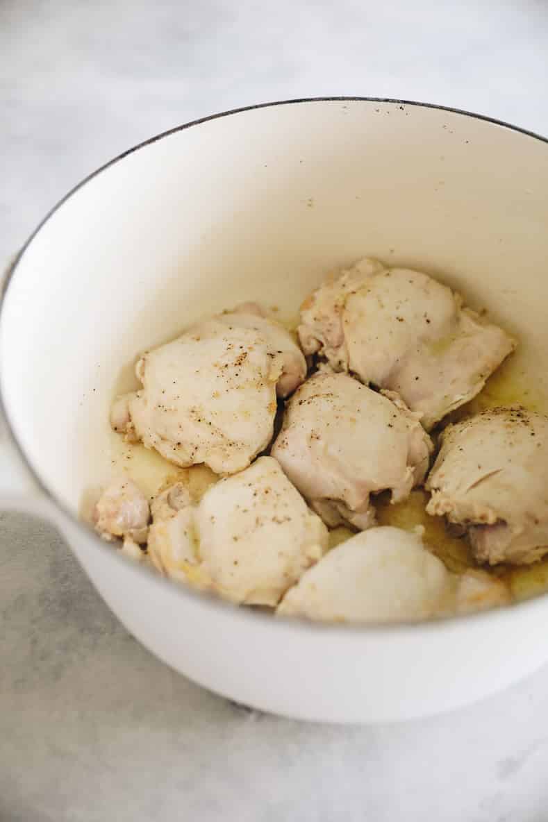 Cooked chicken thighs in a large white pot.