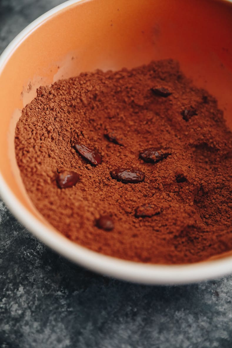 Dark chocolate almonds in an orange mixing bowl with dry mixture.