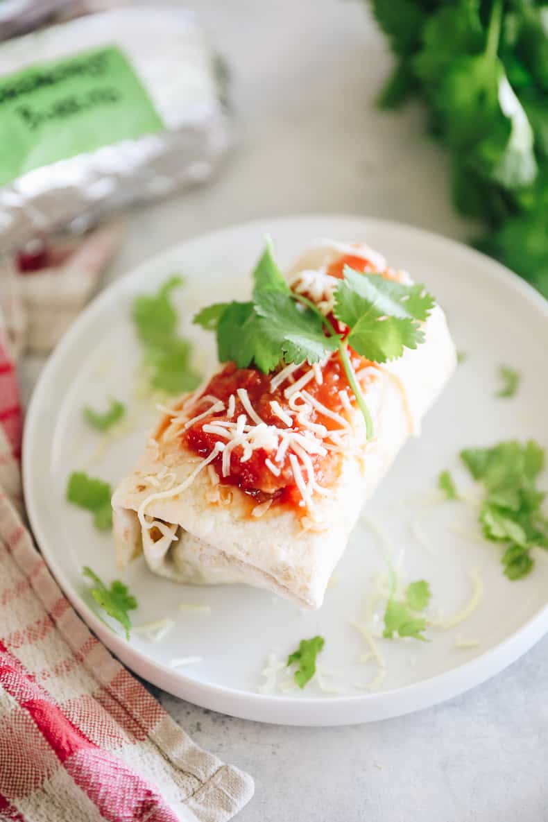 Prepared and reheated breakfast burritos topped with salsa, shredded cheese and cilantro.