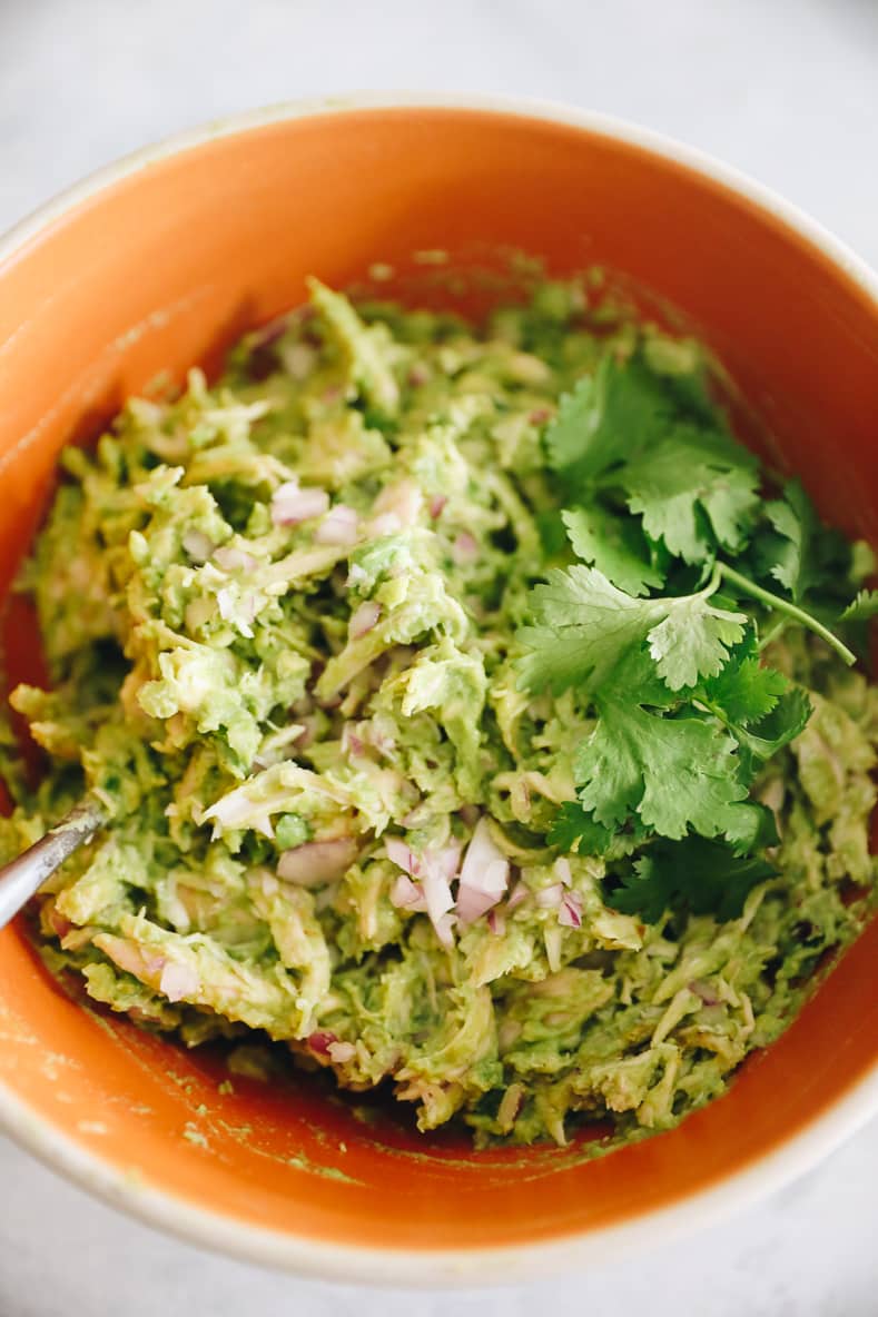 Overhead shot of guacamole chicken salad in orange mixing bowl.