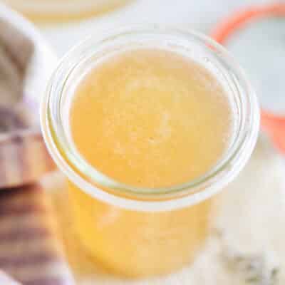 Close up angled shot of lavender simple syrup in a glass storage jar.