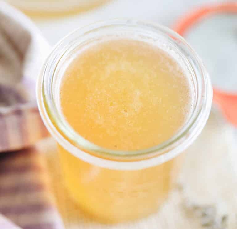 Close up angled shot of lavender simple syrup in a glass storage jar.