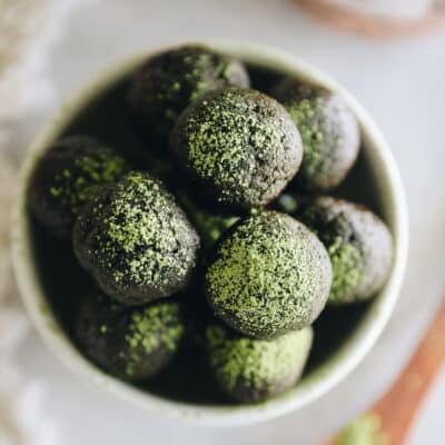 Overhead shot of matcha chocolate energy balls in a white bowl.