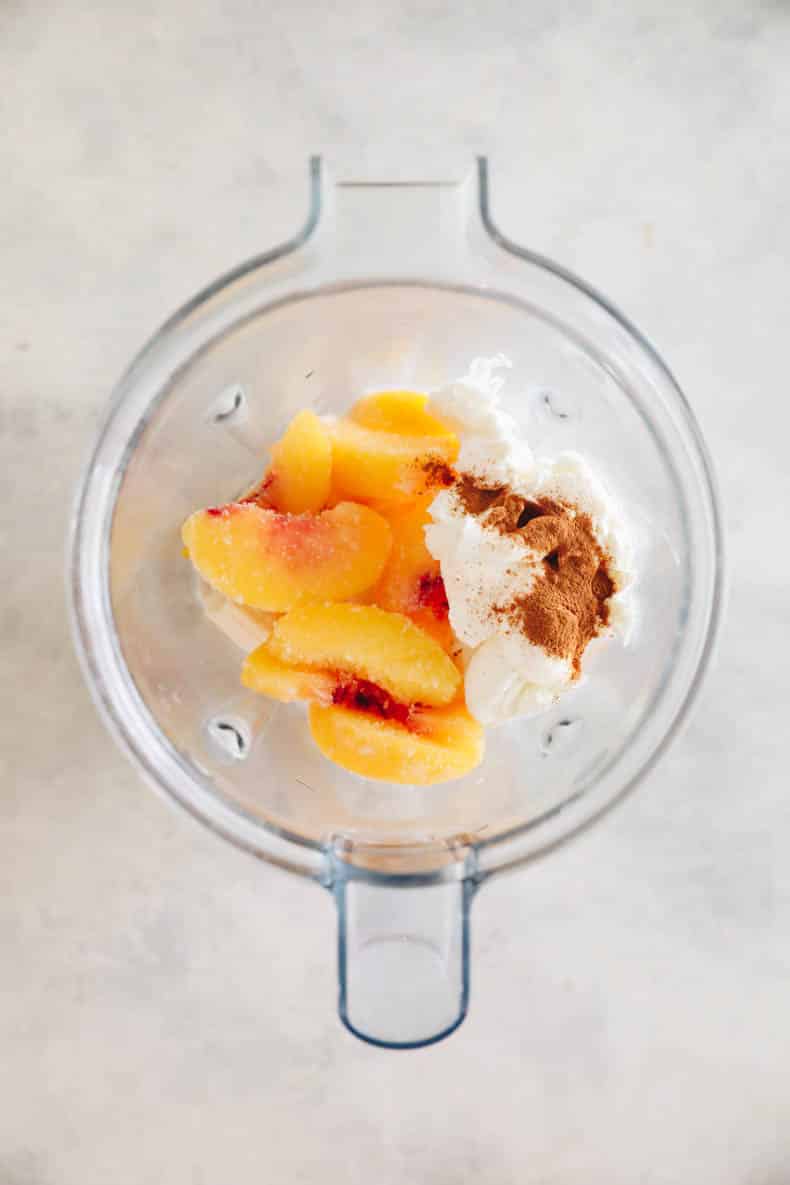 frozen peaches and other smoothie ingredients in a blender.