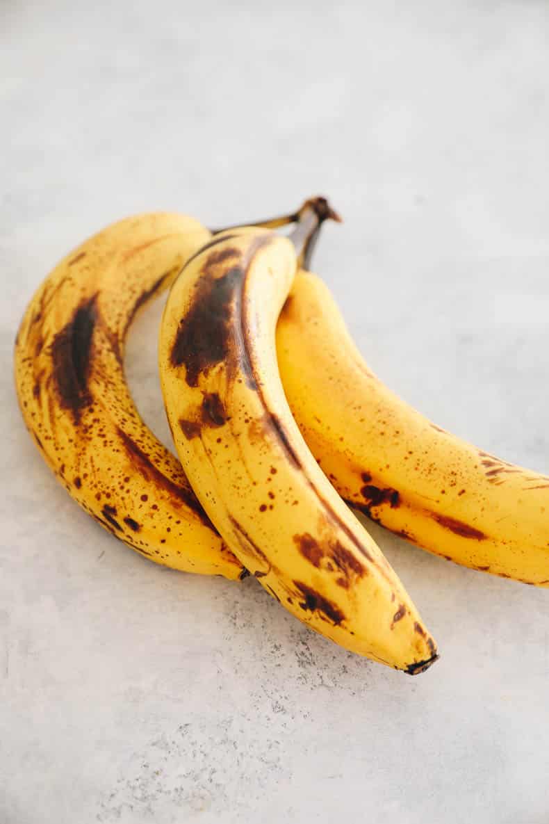 3 ripe bananas with brown spots on a white table