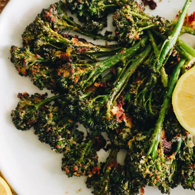 roasted broccolini with lemon on a white plate with parmesan.