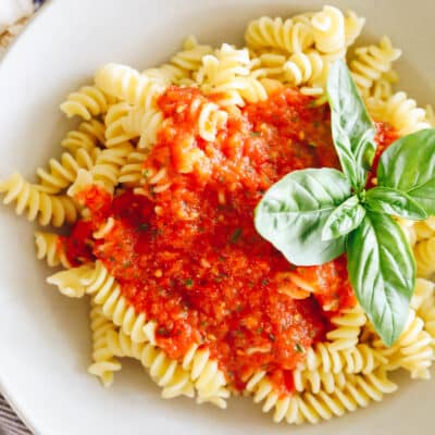 roasted red pepper sauce in a shallow white bowl with fresh basil.