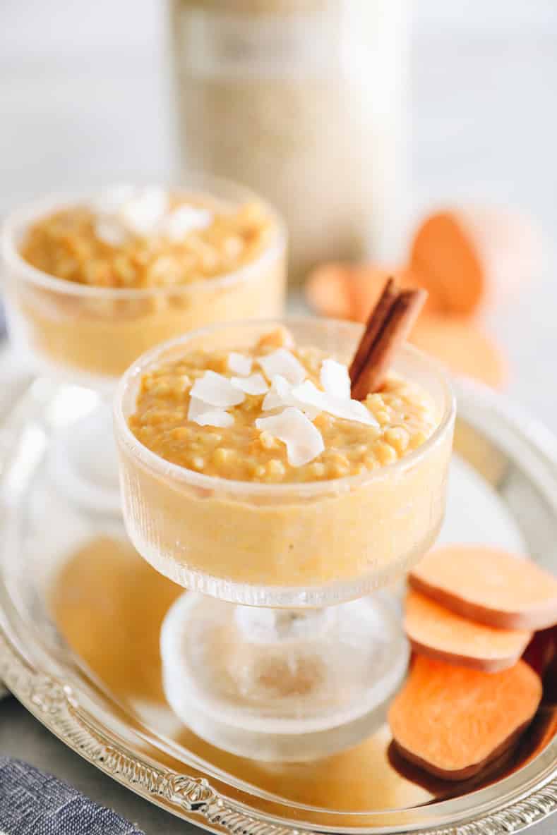 Sweet potato rice pudding in a clear serving dish with shredded coconut and a cinnamon stick on top.